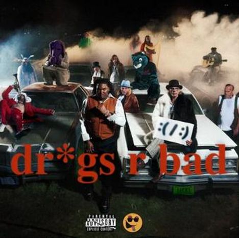 Text: "dr*gs r bad". Eine Gruppe von Personen und Maskottchen steht auf und um zwei Autos in einer Rauchlandschaft.