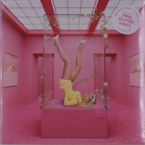 Text: "Pink Glitter Vinyl." Eine Frau in gelbem Outfit in einem gläsernen Kasten in einem pinken Raum.