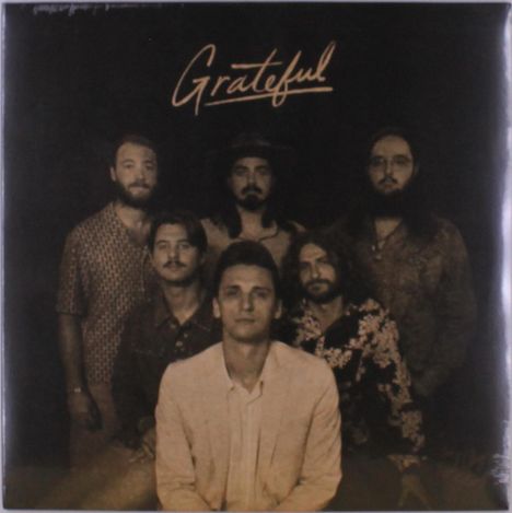 Text: "Grateful" in eleganter Schrift. Sechs Männer, teils mit Bart, stilvoll gekleidet in einem Gruppenportrait.