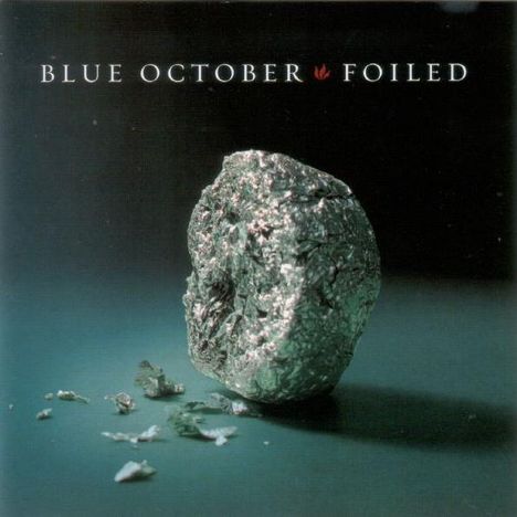 Text: "BLUE OCTOBER FOILED". Eine zerknüllte Alufolie liegt auf einer Oberfläche, spärlich beleuchtet.