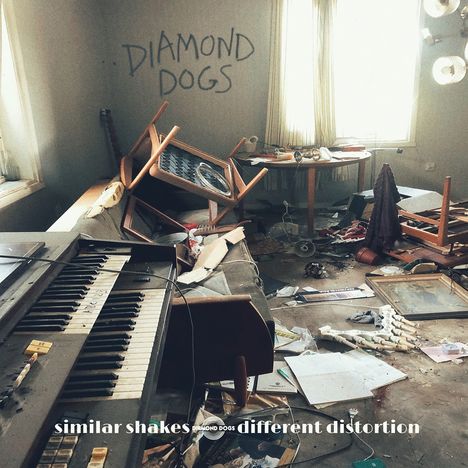 "DIAMOND DOGS" steht an der Wand. Ein Raum voller Chaos mit umgestürzten Möbeln und einem alten Keyboard.