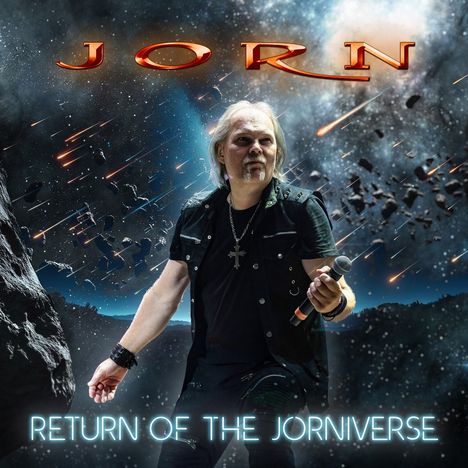 "JORN" oben, "RETURN OF THE JORNIVERSE" unten. Ein Mann hält ein Mikrofon vor einem Weltraumhintergrund mit Meteoren.