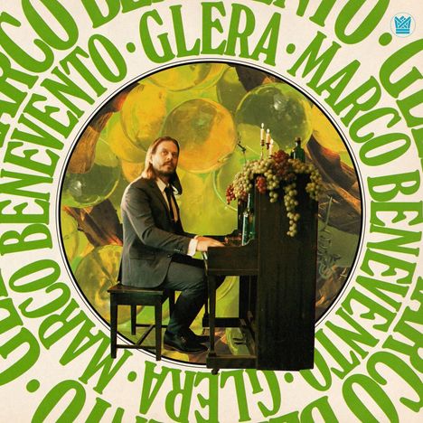 „Marco Benevento, GLERA“ steht in grünen Buchstaben. Ein Mann im Anzug spielt Klavier, mit Trauben dekoriert.