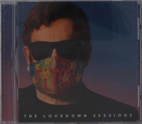 "The Lockdown Sessions." Eine Person mit Sonnenbrille trägt eine bunte Maske mit dem Wort "Elton" und Sternen.