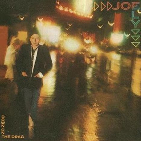 Texte: "JOE ELY", "DOWN ON THE DRAG". Verschwommene Szene einer nächtlichen Stadt mit beleuchteten Schildern, Person im Vordergrund.