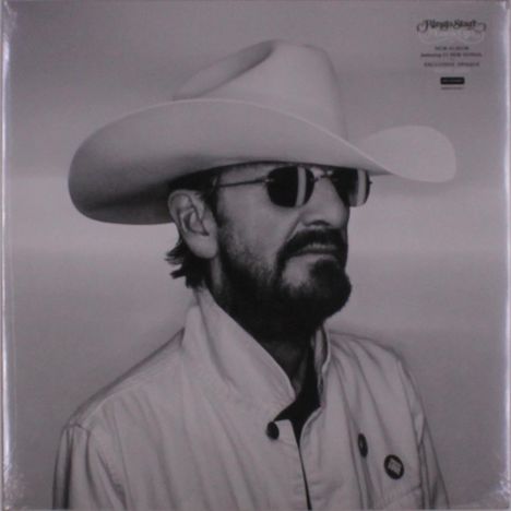 Ein Mann mit Sonnenbrille und weißem Cowboyhut. Er trägt einen Bart und eine helle Jacke.