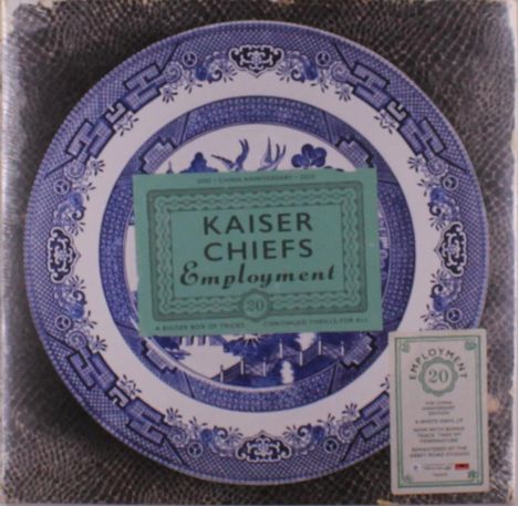 Grüne Karte mit "Kaiser Chiefs Employment" auf blauem Teller mit floralen Mustern und Vögeln. Vintage-Stil.