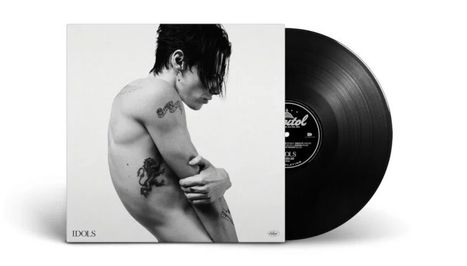 Text: IDOLS  
Schwarz-weißes Foto eines tätowierten, oberkörperfreien Menschen, der eine Schallplatte hält.