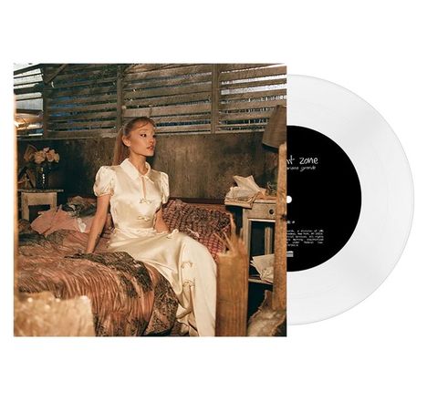 Text: "sweetener", "ariana grande". Eine Frau im Seidenkleid sitzt auf einem Bett in einem rustikalen Raum. Eine Schallplatte ist sichtbar.