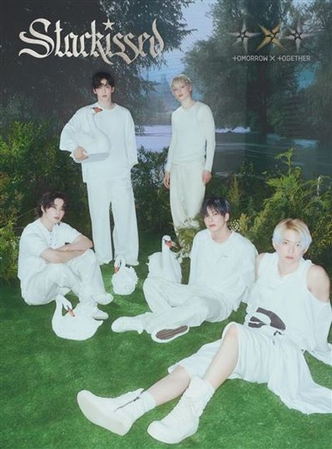 Text: "Stuckissed", "+OMORROW X +OGETHER". Fünf junge Männer in weißer Kleidung auf einer Wiese, umgeben von Schwänen.