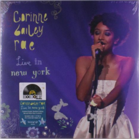 "Corinne Bailey Rae Live in New York." Sängerin mit Mikrofon, violetter Hintergrund, Aufkleber mit Schallplatte.
