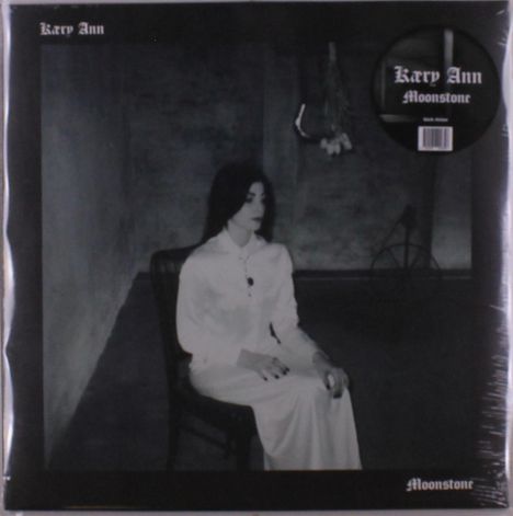 "Kacy Ann", "Moonstone" und "Rich Media" sind die sichtbaren Texte. Eine Frau in Weiß sitzt in einem dunklen Raum.