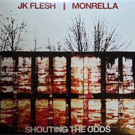 "JK FLESH | MONRELLA" oben, "SHOUTING THE ODDS" unten. Oben kahle Bäume, unten rostige Metallwand.