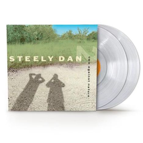 „Steely Dan – Two Against Nature“. Zwei Schatten auf einem Weg vor einem grasbewachsenen Hintergrund. Zwei Schallplatten.