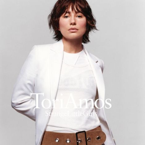 "Tori Amos, Strange Little Girls" steht in weißem Text. Eine Person in weißem Blazer und weißem Shirt blickt nach vorn.