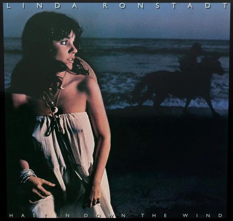 "Linda Ronstadt, Hasten Down the Wind". Eine Frau schaut nach links, ein Reiter im Hintergrund am Strand.