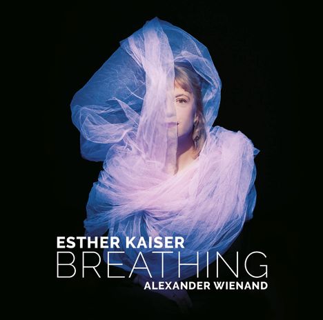 Text: Esther Kaiser Breathing Alexander Wienand. Eine Frau in lila Tuch gehüllt, umgeben von Dunkelheit.