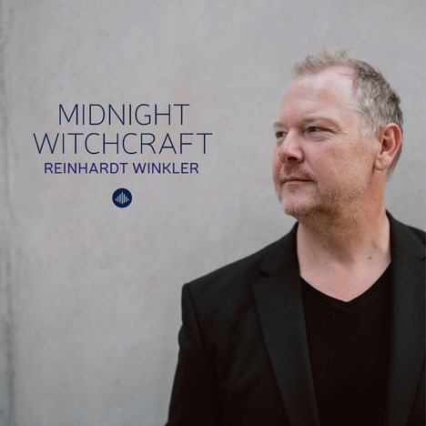 Text: "MIDNIGHT WITCHCRAFT REINHARDT WINKLER". Mann in schwarzem Anzug schaut nach rechts. Grauer Hintergrund.