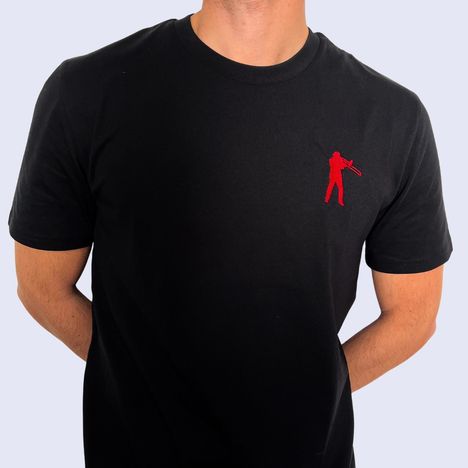 Rotes, kleines Logo einer Person mit Trompete auf schwarzem T-Shirt. Person hat die Hände hinter dem Rücken.