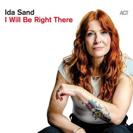 Ida Sand, I Will Be Right There. Frau mit roten Haaren, weißem Top, einem Arm-Tattoo.