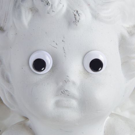 Eine weiße Engelsstatue mit aufgeklebten Wackelaugen, die humorvoll wirken.