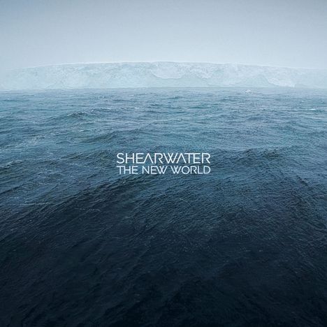 „SHEARWATER THE NEW WORLD“. Weite, dunkle Meeresfläche mit blassem Horizont und entfernten Eisklippen.