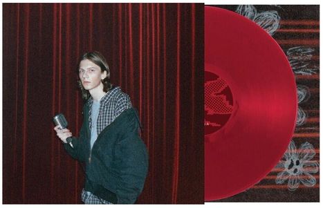 Eine Person mit Mikrofon steht vor roten Vorhängen, daneben eine rote Schallplatte mit stilisiertem Muster.