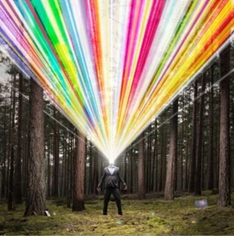 Kein Text vorhanden. Ein Mann im Anzug steht in einem Wald, aus seinem Kopf strahlen bunte Lichtbündel.