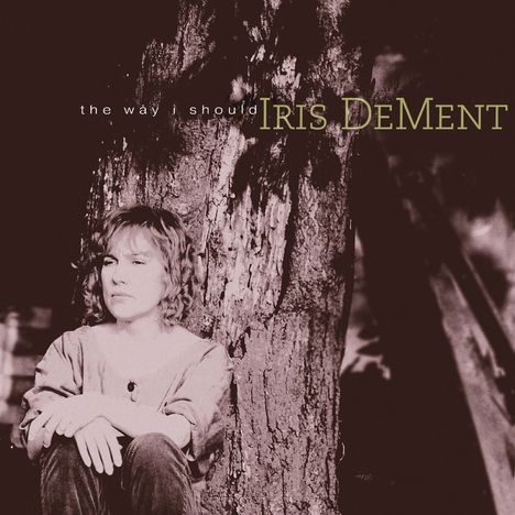 Text: "the way I should" und "IRIS DeMENT". Eine Person sitzt nachdenklich an einen Baum gelehnt.