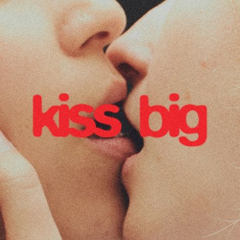Text: "kiss big." Zwei Gesichter beim Kuss, Nahaufnahme. Text in roter, kräftiger Schrift überlagert die Szene.