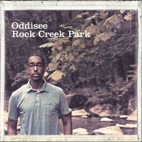 Text: "Oddisee Rock Creek Park". Ein Mann steht in einem Wald, trägt ein blaues Hemd und hinter ihm fließt ein Bach.