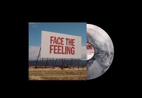 „FACE THE FEELING“ auf einer großen Werbetafel vor einem Himmel, mit einer Schallplatte im Hintergrund.