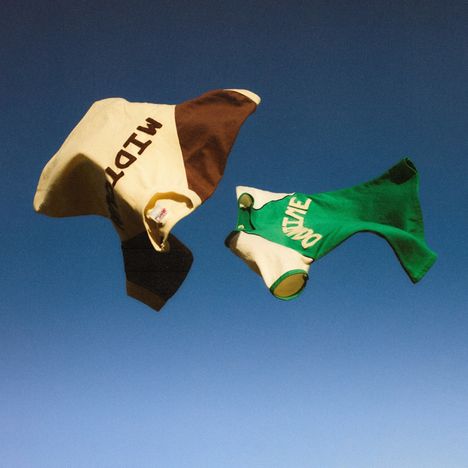 Text: "MID" auf braun-beigem Kleidungsstück, "DOWIE" auf grünem. Zwei Kleidungsstücke schweben vor blauem Himmel.