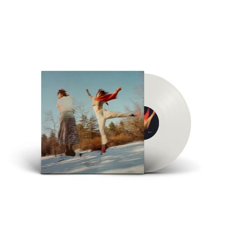 Zwei Personen tanzen auf einer schneebedeckten Fläche, der Himmel ist blau. Ein Albumcover mit einer weißen Schallplatte.