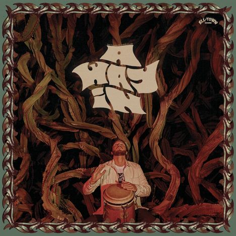 „Mitchell Gagoue“ oben, „Keleketla!“ mittig. Mann spielt Trommel, umgeben von Kakteen, dunkles Ambiente.