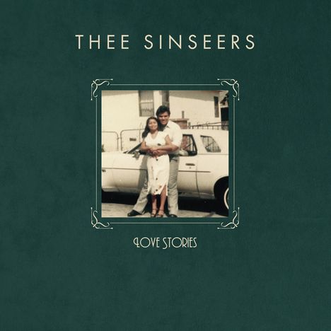 Text: THEE SINSEERS, LOVE STORIES. Ein Paar umarmt sich vor einem Auto.