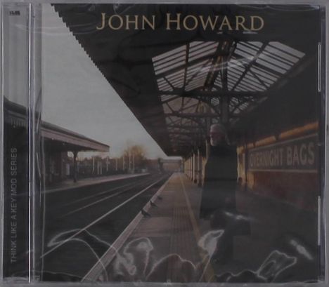 Texte: "JOHN HOWARD", "OVERNIGHT BAGS", "THINK LIKE A KEY MOD SERIES". Eine Person steht auf einem Gleis unter einem überdachten Bahnsteig.