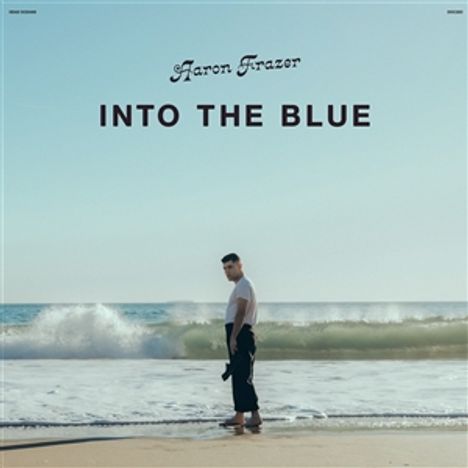 "Aaron Frazer - INTO THE BLUE." Ein Mann steht am Strand, blickt aufs Meer mit sanften Wellen und hellem Himmel.