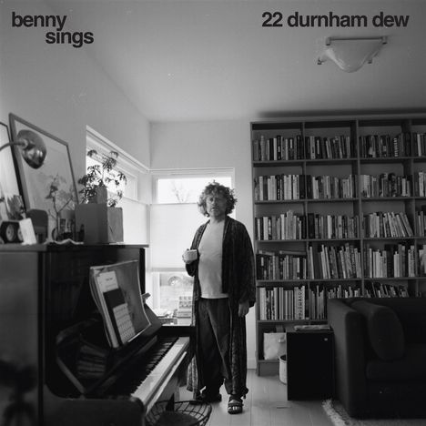 „benny sings“ und „22 durnham dew“ oben. Eine Person steht mit Tasse in einem Zimmer mit Büchern und einem Klavier.