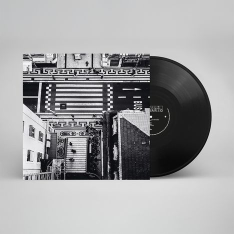Schwarz-weißes Luftbild einer Straße mit „BUS”-Markierung, Zebrastreifen und Architektur. Vinyl auf der rechten Seite.