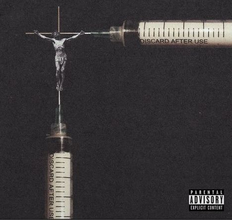 Text: "DISCARD AFTER USE". Darstellung: Jesus am Kreuz, gebildet aus Spritzen.