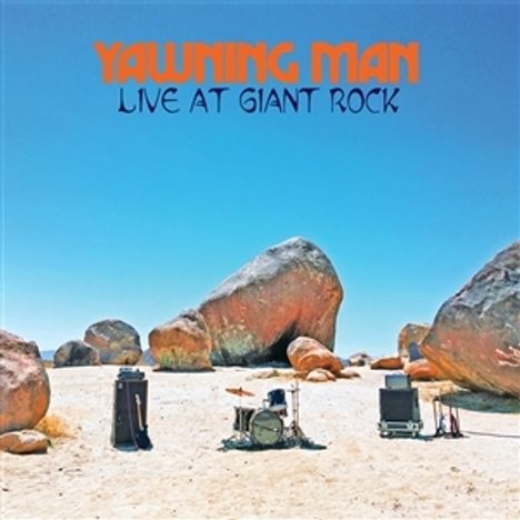 "YAWNING MAN LIVE AT GIANT ROCK" in orange und blauem Text. Im Hintergrund eine Wüstenlandschaft mit großen Felsen.