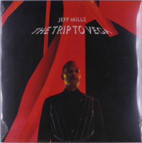 Text: "Jeff Mills The Trip to Vega". Eine Person in schwarzer Kleidung vor einem Hintergrund mit großen roten Formen.
