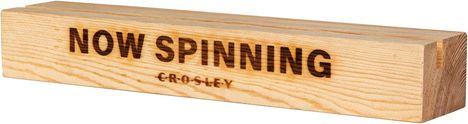 "NOW SPINNING" gefolgt von "CROSLEY" auf einem rechteckigen Holzblock.