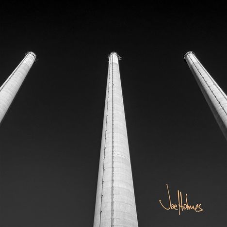 Unterschrift "Joe Holmes", drei hohe Schornsteine ragen in den dunklen Himmel hinauf.