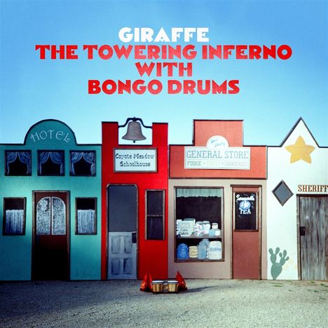 Texte: "GIRAFFE THE TOWERING INFERNO WITH BONGO DRUMS", "Hotel", "Coyote Meadow Schoolhouse", "General Store", "Sheriff". Bunte Fassaden.