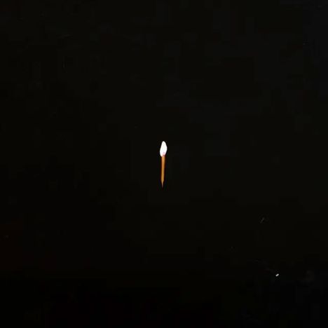 Keine Texte erkennbar. Ein Streichholz brennt allein in der Dunkelheit.