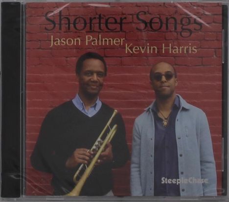 "Shorter Songs", Jason Palmer und Kevin Harris. Zwei Männer vor einer roten Ziegelwand, einer hält eine Trompete.