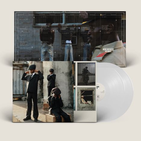 Texte: "HERE BECAUSE OF HOPE". Drei Jungen in Anzügen, einer sitzt, zwei stehen. Vinyl-Schallplatte in Weiß.