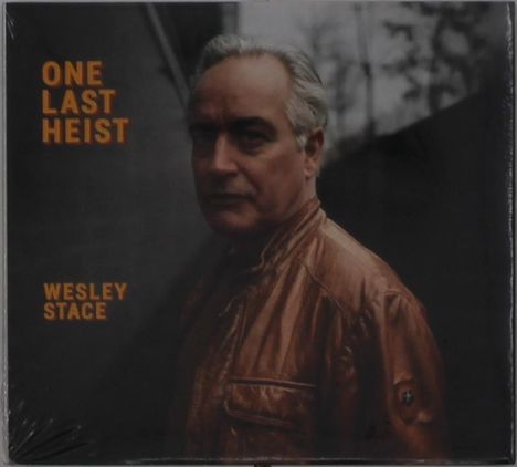 Texte: "ONE LAST HEIST", "WESLEY STACE". Im Hintergrund: Ein Mann in Lederjacke, ernster Blick, dunkler, unscharfer Hintergrund.